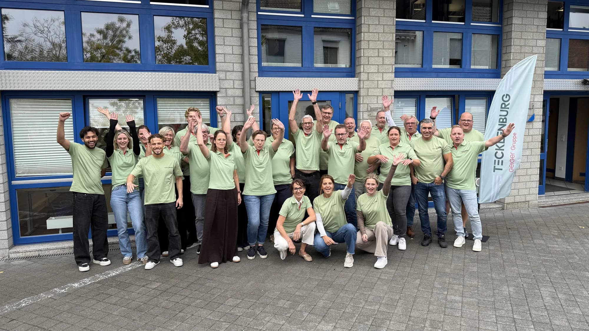 Het juichende team van Tecklenburg GmbH voor het bedrijfspand, in de polo's van de nieuwe merkidentiteit